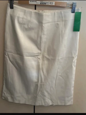 Vit pennkjol i bomull - Klassisk vit pennkjol i bomull med rak passform och diskret slits bak. Kjolen har en enkel design med dold dragkedja bak och passar perfekt till både vardags- och trendiga outfits.