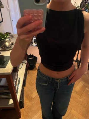 Svart omlott linnetopp i satin - Snygg svart omlott linnetopp i satin med knyt i midjan. Toppen är ärmlös och har en croppad passform som ger en trendig look. Perfekt att styla med jeans eller kjol för en cool outfit. Säljs inte längre. Skriv om det finns några funderingar eller för fler bilder❣️