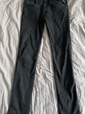 Replay Jeans Anbass - Säljer ett par svarta jeans med rak passform och klassisk femficksdesign. Jeansen har en snygg dragkedjedetalj vid ena fickan fram och är tillverkade i ett mjukt denimtyg. Perfekta för en stilren och avslappnad look.