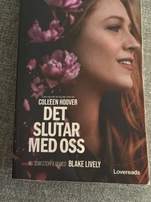 Det slutar med oss av Colleen Hoover - En gripande roman av Colleen Hoover med ett omslag i svart och rosa toner, prydd med blommor och ett porträtt. Boken är på svenska och handlar om kärlek, svåra val och relationer. Perfekt för dig som gillar starka känslor och dramatik.