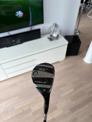 Cleveland Launcher XL Halo hybridklubba - Cleveland Launcher XL Halo hybridklubba, modell 5. Väldigt lättslagen klubba med nytt golf Pride grepp. Regular projekt X skaft. Svart och silverfärgad med tydliga markeringar på klubbhuvudet. Perfekt för dig som vill ha extra kontroll och längd på golfbanan. Snygg och modern design i metall och komposit.