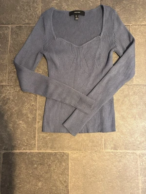 Blå ribbstickad topp från Vero Moda - Trendig blå ribbstickad topp från Vero Moda med lång ärm och markerad sweetheart-urringning. 