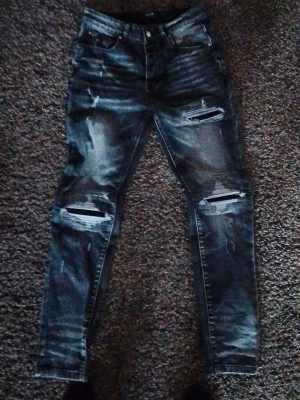 Amiri jeans size 30 Svarta slitna jeans  - ASäljer ett par blå skinny jeans med slitningar och hål på knäna. Jeansen har klassisk femficksmodell, knappgylf och coolt tvättad look. Perfekta för dig som gillar streetstyle och vill ha en edgy vibe.