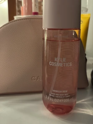 Kylie Cosmetics Vanilla Dew Body Mist - Fräsch och söt body mist från Kylie Cosmetics i doften Vanilla Dew. Flaskan är cylinderformad, genomskinlig med rosa ton och vitt lock. Innehåller 236 ml och kan användas både för hår och kropp. Perfekt för dig som gillar vaniljdoft.