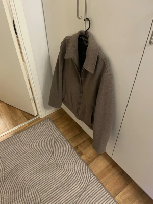 Brun zip cardiganjacka med krage /Overshirt - Snygg brun cardiganjacka med dragkedja framtill och klassisk krage. Jackan har raka ärmar och en minimalistisk design som passar till det mesta. Materialet ser ut att vara ullblandning för extra värme och stilren look.