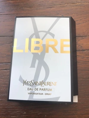Yves Saint Laurent Libre Eau de Parfum 1,2 ml - Säljer en elegant parfym från Yves Saint Laurent, Libre Eau de Parfum. Förpackningen är vit med guldtext och har den ikoniska YSL-loggan. Perfekt för dig som vill ha en lyxig och modern doft i din samling.
