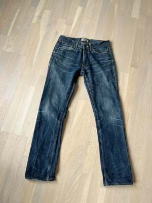 Acne studios Jeans  - Säljer ett par mörkblå jeans från Levi's med raka ben och klassiska fem fickor. Jeansen har snygga slitningar och kontrastsömmar, vilket ger en cool och avslappnad look. Materialet är robust denim och passformen är normal.