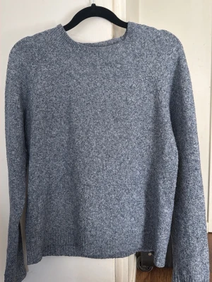 Gråmelerad stickad tröja Vero Moda - Mysig gråmelerad stickad tröja från Vero Moda. Tröjan har rund halsringning, långa ärmar och ribbade muddar vid hals, ärmslut och nederkant. Perfekt för lager på lager och enkel att matcha till olika outfits.