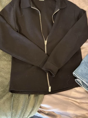 Svart zip hoodie från Selected Homme - Snygg svart hoodie från Selected Homme med dragkedja framtill och klassisk krage. Tillverkad i mjukt bomullsmaterial som känns skönt mot huden. Perfekt för en avslappnad och stilren look.