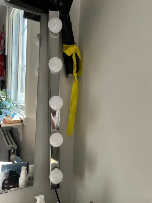 Sminkspegel med LED-lampor - Sminkspegel med rektangulär form och silverram, utrustad med fem stora runda LED-lampor för optimal belysning. Perfekt för att få till sminket i detalj. Spegeln har en modern design och passar snyggt på sminkbordet.