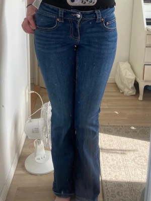 Mörkblå bootcut jeans från Crocker - Säljer ett par mörkblå bootcut jeans från Crocker med klassisk femficksdesign och snygga kontrastsömmar. Jeansen har knapp- och dragkedjestängning samt fickor med lock och knapp bak. Perfekta för en avslappnad och trendig look.