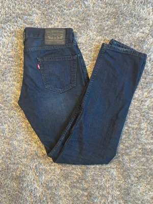 Levi's 511 - Snygga mörkblå jeans från Levi's i modellen 511 slim med klassisk femficksdesign och rakt ben. Jeansen har en diskret tvättad look och Levi's röda etikett på bakfickan. Tillverkade i slitstark denim som ger en tidlös och cool stil. Storlek W30 & L32