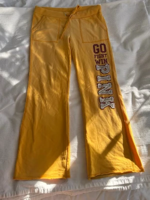 Gula mjukisbyxor från Victoria's Secret - Gula mjukisbyxor från Victoria's Secret PINK med breda ben och snörning i midjan och Stora fickor framtill. Mjukt bomullsmaterial som är riktigt skönt att ha på sig. Snygga till sommaren😍