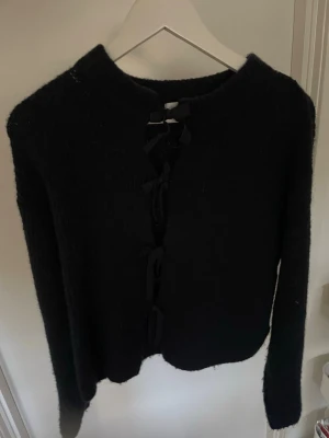 Marinblå kofta med knytning framtill - Cool marinblå kofta med knytning längs hela framsidan. Mjuk och fluffig känsla, perfekt att slänga på sig när det är lite kyligt. Långärmad och med rund halsringning. Passar dig som gillar en enkel men ändå unik stil.