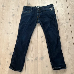 Mörkblå raka jeans med kontrastsömmar - Säljer ett par mörkblå jeans från Replay med raka ben och snygga kontrastsömmar. Klassisk femficksmodell med knappgylf och detaljer på bakfickorna. Perfekta för dig som gillar en enkel men stilren look.priset är ej hugget i sten 🪨 