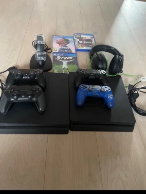 PlayStation 4 Slim med tillbehör - Säljer ett komplett PS4-paket som är köpt för cirka 3 år sedan och fungerar utan problem. Perfekt för dig som vill komma igång direkt eller uppgradera med extra tillbehör.  Detta ingår: • 2 st PlayStation 4-konsoler • 4 st handkontroller (3 svarta, 1 blå) • Headset med mikrofon • Laddstation för kontroller • Kablar (ström + HDMI) • 3 spel: FIFA 22, FIFA 18 och EA Sports FC 25  Allt är i bra skick och redo att användas direkt.  Säljes som paket, men kan diskuteras vid snabb affär.