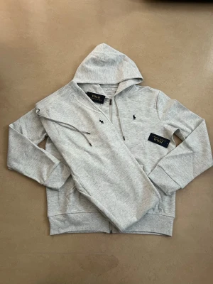 Ralph lauren tracksuit grå storlek medium  - Helt ny Ralph Lauren tracksuit (hoodie + byxor). En av de mest efterfrågade seten – perfekt för vardag och resor.  • Oanvänd / nyskick • Säljs som komplett set • Väldigt populär modell • Bekväm och stilren passform • Perfekt året runt  Storlek: M Färg: grå   Skickas snabbt 📦 Rabatt vid köp av flera plagg.