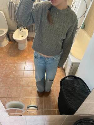 Grå stickad tröja från H&M - Säljer en grå stickad tröja från H&M i storlek XS. Tröjan har ett klassiskt kabelstickat mönster, rund halsringning och ribbade muddar vid ärmslut och nederkant😍