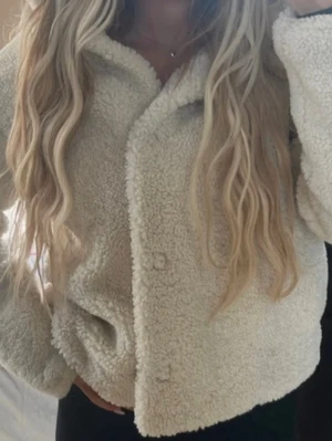 Mango Teddyjacka - Säljer denna Teddy jackan då den inte kommer till användning. Jackan har en luva som är perfekt för regniga dagar och för en söt look. Jackan har dock en knapp som ej vill stänga när man vill knäppa jackan (bild 4 & 5).