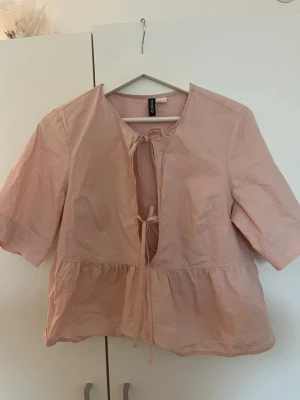 Ljusrosa blus med knyt från HM - Söt ljusrosa blus med knytband framtill och avslappnad passform. Använd 2 gånger 