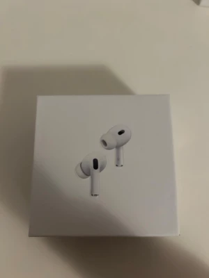 AirPods trådlösa hörlurar - Säljer ett par vita AirPods med laddningsetui. Snygg och kompakt design i plast, perfekt för dig som vill ha grymt ljud. Smidiga att ta med överallt och passar till både iPhone och andra enheter med Bluetooth.