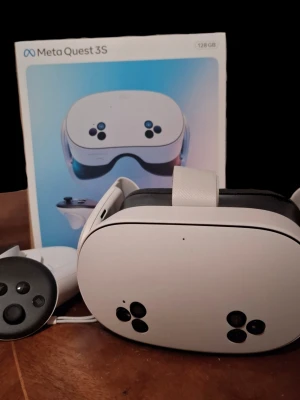 Meta Quest 3S VR-headset 128GB - Meta Quest 3S VR-glasögon med 128GB lagring. Setet innehåller ett vitt headset med svarta detaljer, justerbart huvudband och två matchande handkontroller. Modern design i plast och tyg för bekväm passform. Perfekt för gaming och VR-upplevelser.
