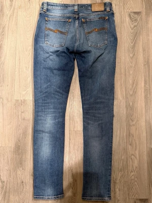 Nudie Jeans Blå W30 L32 - Fint skick. Storlek W30/L32. Mått - Midja: 40cm, Ytterbenslängd: 105cm, Benöppning: 15. Modellen är 185cm & 63kg. Hör av dig vid funderingar!🤝