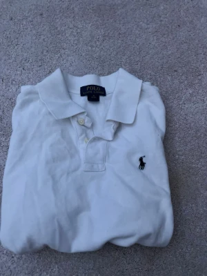 Vit pikétröja från Polo Ralph Lauren - Klassisk vit pikétröja från Polo Ralph Lauren med korta ärmar. Tröjan är storlek M men passar xs bäst. Kontakta vid minsta fundering