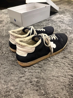 The Gallerist navy blue skor - Mörk blå (ser ut som svart på bilderna) the gallerist skor med vita detaljer och beige sula. Skorna har vitt fuskpälsfoder för extra komfort och en klassisk låg siluet, perfekt för vintern. Perfekta för dig som vill ha en unik touch på dina sneakers. Snörning framtill och kontrastdetaljer på hälen. Riktigt sköna skor generellt och snygga. 