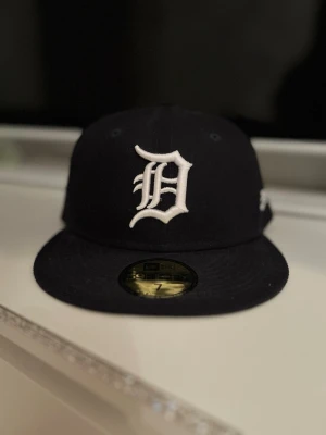 New Era Detroit Tigers keps - Snygg svart keps från New Era med Detroit Tigers-logga broderad i vitt framtill och New Era-logga på sidan. Klassisk flat brim och 59Fifty-modell. Är knappast använd, små möjliga avfärgningar på insidan endast.