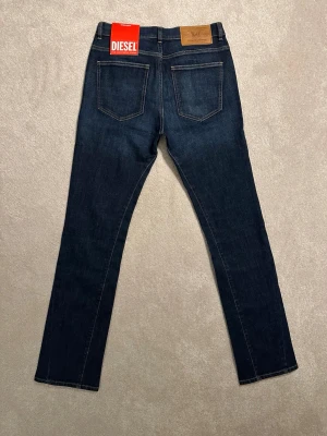 Diesel Bootcut Jeans - 29/32  - Nypris : 1499 kr. NYA MED PRISLAPP. Snygga mörkblå jeans från Diesel i storlek W29 L32 med klassisk femficksdesign, raka ben och Bootcut. Jeansen har kontrastsömmar och en läderpatch med logga bak i midjan. Materialet är denim i bomull med en skön känsla. 