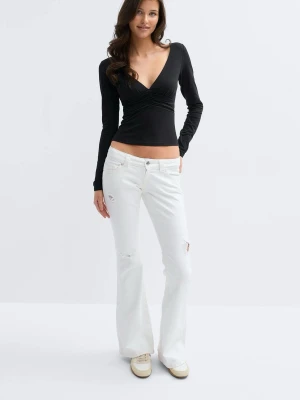 Vita lågmidjade bootcut jeans - Säljer ett par vita bootcut jeans med slitna detaljer. Jeansen har låg midja och ett stretchigt material. Ny skick, ny pris 400