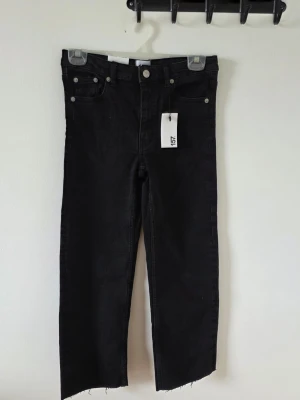 Svarta raka jeans från Lager 157 - Snygga svarta jeans  med raka ben och rå kant nertill. Klassisk femficksmodell med silverfärgade nitar och knapp. Jeansen har en trendig tvättad look och är tillverkade i ett mjukt denimtyg som känns bekvämt.