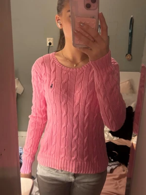 Rosa  Polo Ralph Lauren Tröja  - Supersnygg rosa kabelstickad tröja från Polo Ralph Lauren med rund halsringning och den klassiska broderade loggan på bröstet. Knappt använd och jättefint skick!! Är strl M men passar mig som är S 