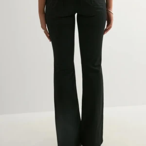 Svarta bootcut jeans från Nelly - Snygga svarta bootcut jeans från Nelly  med låg midja och utsvängda ben. Jeansen har klassisk femficksdesign och är tillverkade i ett stretchigt denimtyg som sitter bekvämt. Perfekta för en trendig och avslappnad look.