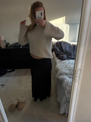 Svart långkjol i satin-look - Säljer en svart långkjol med snygg satin-finish. Kjolen har en enkel, rak passform som faller snyggt längs benen och ger en clean och stilren vibe. Perfekt att styla med en stickad tröja eller crop top.