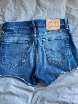 Levi's vintage blå jeansshorts  - Säljer ett par klassiska blå jeansshorts från Levi's med avklippt kant och två bakfickor. Perfekta för sommardagar och enkel att matcha med allt. De är mellan storlek S och M. Alltså W29 L.32