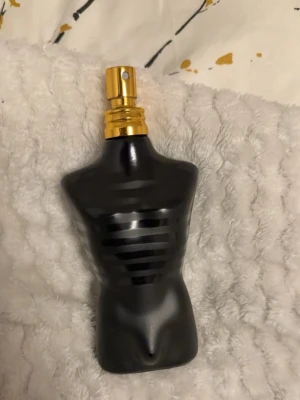 Jean Paul Gaultier Le Male parfym 125ml ca 120ml kvar - Klassisk parfymflaska från Jean Paul Gaultier formad som en manlig torso i svart och mörkgrått med matta och blanka ränder. Flaskan har en guldfärgad spraytopp och är tillverkad i glas. En ikonisk doft för dig som vill sticka ut.