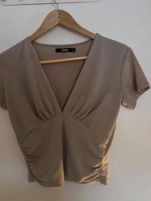 Beige v-ringad tishirt från Bikbok - Beige v-ringad tishirt från Bikbok i storlek S. 💕
