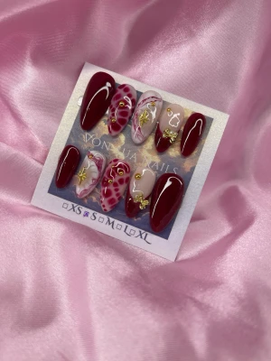 Rouge (S);Medium Almond - Snygga handgjorda press-on naglar i en medium mandelform. Färgerna är vinrött, vitt och nude med detaljer som hjärtan, leopardmönster och guldfärgade dekorationer. Mixade mönster och 3D-effekter ger en unik look. Perfekt för dig som vill sticka ut med dina naglar!S: 15 mm, 11,5 mm, 12 mm, 11 mm, 9 mm 