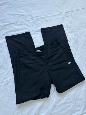 Adidas byxor  - Säljer ett par svarta byxor från Adidas med klassisk logga på vänster ben. Byxorna har resår i midjan och raka ben. Vid köp av flera varor får du rabatt 