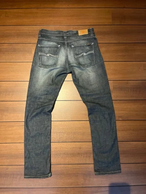 Nudie Jeans Grim Tim - Riktigt feta Nudie jeans i en unik ljusgrå tvätt med vita detaljer. Modell Grim tim med slim-straight passform i storlek W33 L32. 41-42cm i midjan och innerben cirka 75-76. 