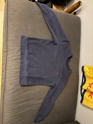 Mörkblå sweatshirt från Polo Ralph Lauren - Klassisk mörkblå sweatshirt från Polo Ralph Lauren med rund halsringning och den ikoniska röda logotypen broderad på bröstet. Tröjan har långa ärmar och ribbade muddar vid ärmslut och nederkant. Perfekt för en avslappnad och stilren look. Den ser ut att vara en konstig färg på tröjan på bilderna fast det är min kamera och ljuset som är lite konstigt 