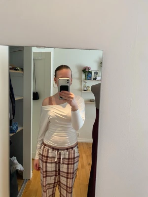 Vit offshoulder långärmad topp - Säljer en vit offshoulder topp med långa ärmar. Toppen har en tight passform och är tillverkad i ett mjukt, stretchigt material som sitter snyggt på kroppen. Perfekt för dig som gillar en clean och stilren look. Har bara använt tröjan 1 gång.