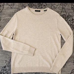 Beige stickad tröja från Jack & Jones - Snygg beige stickad tröja från Jack & Jones med rund halsringning och långa ärmar. Tröjan har en enkel och stilren design med ribbade muddar vid ärmslut och nederkant. Perfekt basplagg för din garderob.
