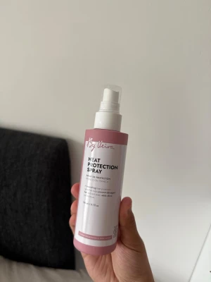 By Veira Heat Protection Spray - Värmeskyddsspray från By Veira i en rosa och vit plastflaska med pump. Sprayen skyddar håret mot värmeverktyg och hjälper till att bevara hårets fukt och glans. Perfekt för dig som ofta stylar håret med plattång eller locktång.
