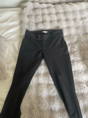 Svarta byxor från Nelly  - Snygga svarta byxor från Nelly med två dekorativa knappar i midjan. Dom har lite kostymbyxa vibe men har mjukisbyxor material. Supersköna och snygga. 