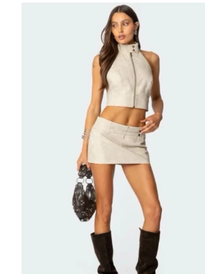 Beige minikjol från Edikted - Trendig beige minikjol i syntetmaterial med tillhörande bälte i midjan. Kjolen har en stilren design och passar perfekt till boots eller sneakers för en cool look. Enkel att matcha med olika toppar för en personlig stil.