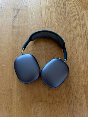 Apple AirPods Max mörkgrå hörlurar - Snygga Apple AirPods Max i mörkgrå färg med stilren design. Hörlurarna har stora, ovala kåpor i aluminium och ett vadderat meshband för extra komfort. Perfekta för musik, gaming eller film med grym ljudkvalitet och modern look.