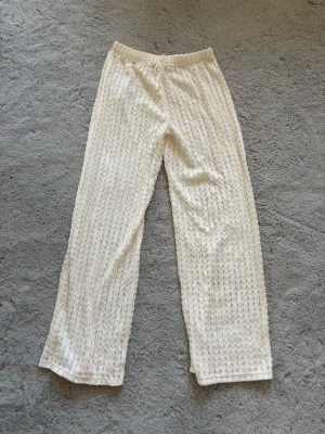 Beige strandbyxor - Säljer ett par beige strandbyxor med raka ben och elastisk midja, perfekta att dra över bikinin på stranden. Materialet känns mjukt och följsamt.